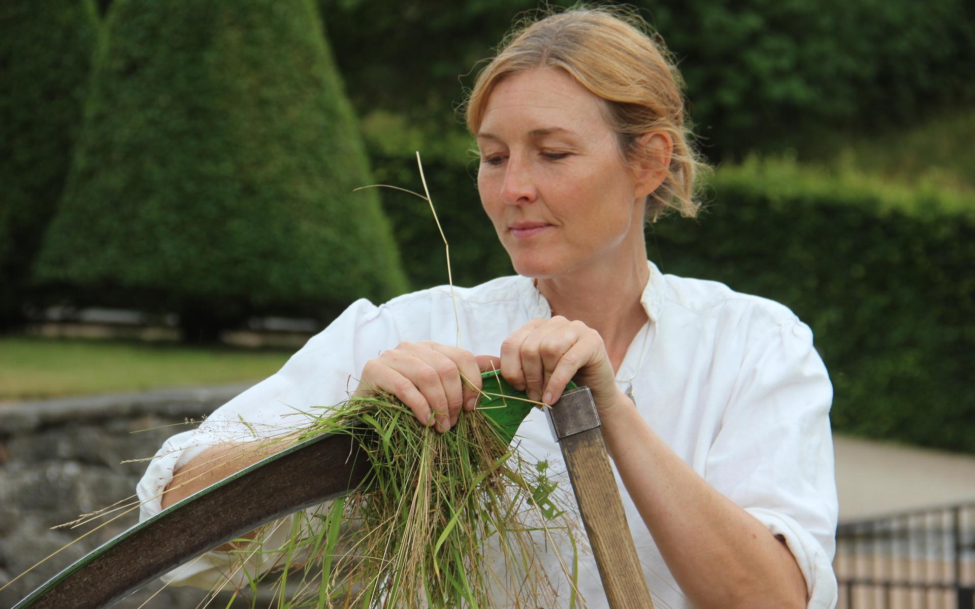 Marica Wettergren använder gräs för att torka av bladet från växtsaft. 