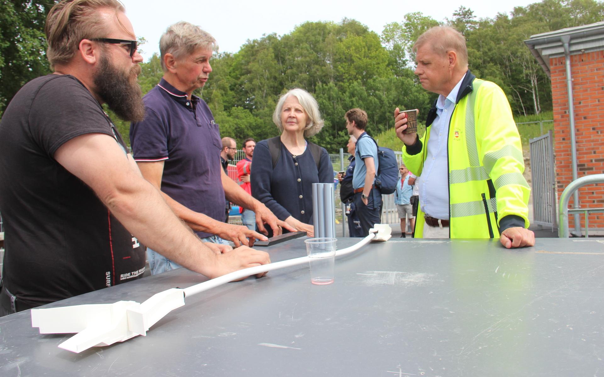 Kristjan Andersson, projektledare vid Veidekke grundläggning, och tekniska förvaltningens chef Göran Werner talar med närboende Ingrid Stenhagen och Klas Ronstrand. På bordet syns en 3D-printad modell av det 200 meter långa betongröret. 
