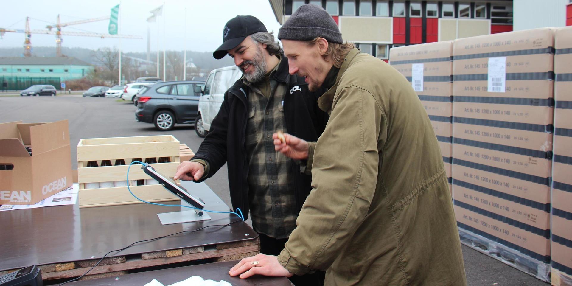 Rodrigo Arvidsson instruerar Marcus Berggren hur kassaapparaten fungerar.