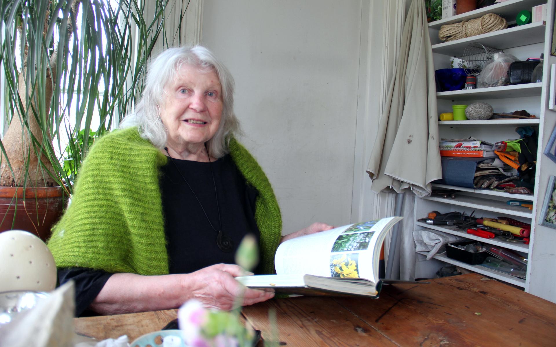 Karin Berglund tittar igenom boken ”Min trädgård” i uterummet.